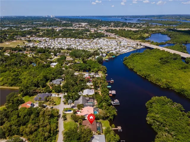 Waterfront property featuring a private boat dock, mature landscaping, and a fenced swimming pool