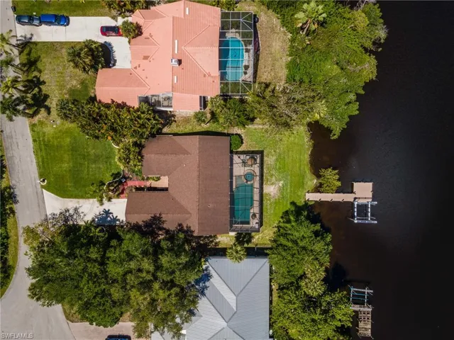 Waterfront property featuring a private boat dock with lift, screened pool area, and mature landscaping