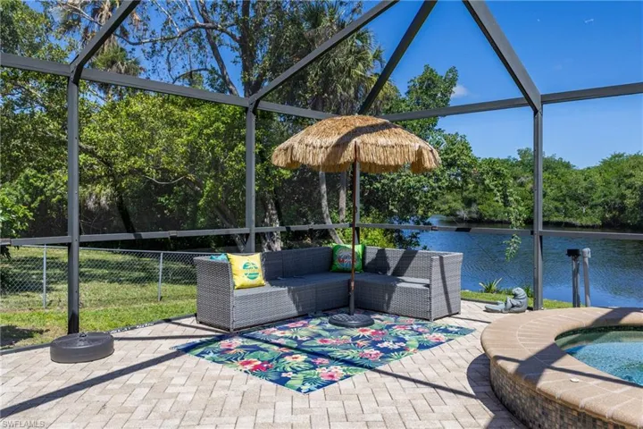 Screened-in outdoor living space featuring a paver patio, integrated spa, and water frontage
