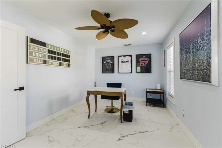 Spacious room featuring white marble-look flooring, light blue walls, and a ceiling fan with leaf-shaped blades