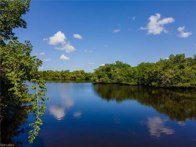 Expansive waterfront with natural tree-lined banks under a clear blue sky