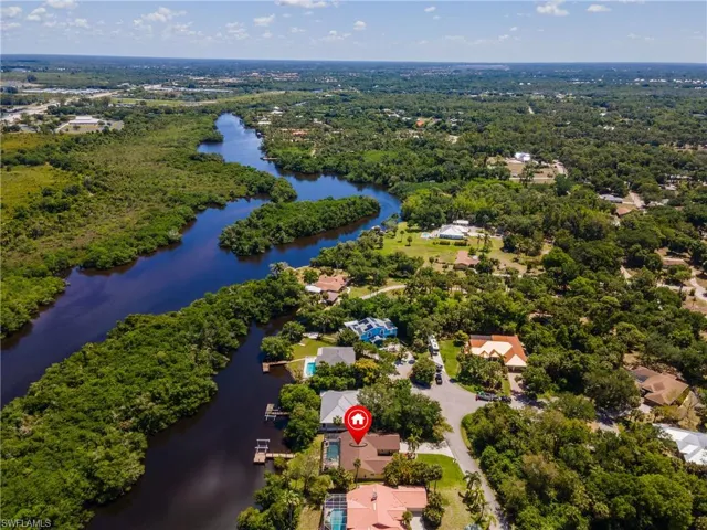 Aerial perspective showcasing a residential property with a private pool and dock access to a winding river