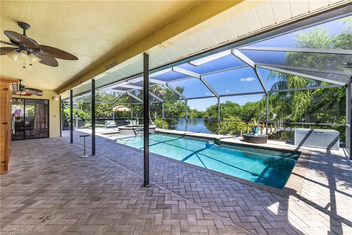 Screened pool enclosure with a rectangular swimming pool, integrated spa, and water frontage