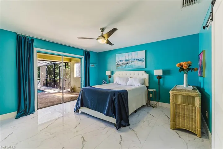 Spacious room featuring white large-format tile flooring, a ceiling fan with integrated lighting, and direct access to an outdoor screened patio and pool through sliding glass doors