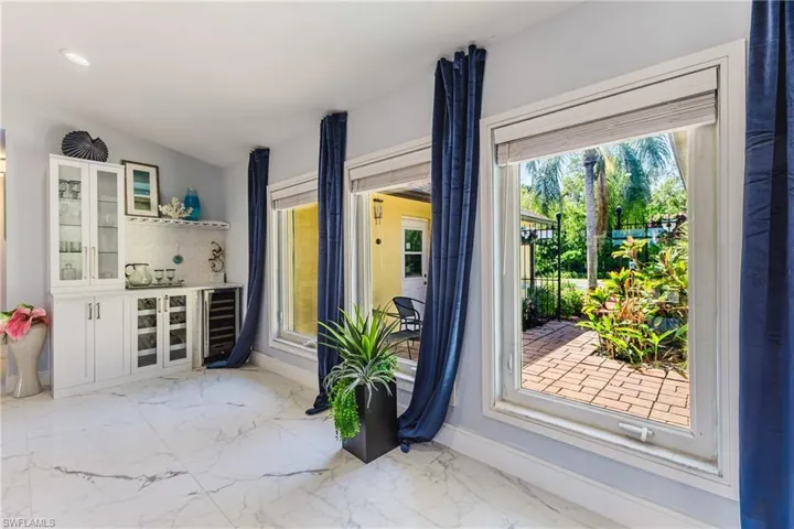 Interior space featuring a built-in wet bar with white cabinetry, a beverage cooler, and a tiled backsplash