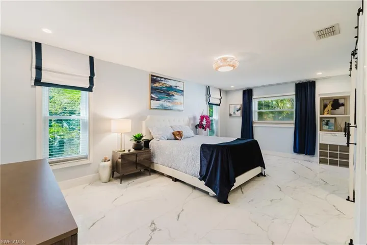 Spacious room featuring large format tile flooring, recessed lighting, and multiple windows