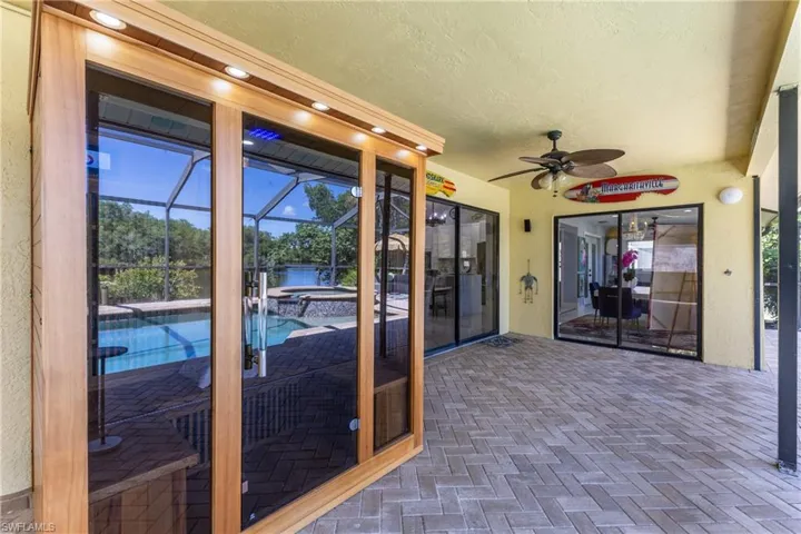 Covered patio featuring paver flooring, a built-in sauna with a glass facade, multiple sliding glass doors, a ceiling fan, and recessed lighting