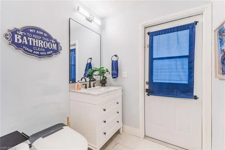 Bathroom featuring a white vanity with a light-toned countertop, a rectangular mirror, and an adjacent white door with a window