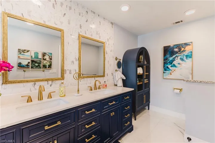 Dual vanity with a white countertop and navy cabinetry, featuring gold hardware and fixtures