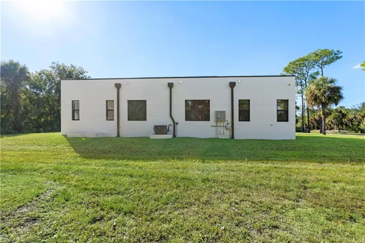 Rear view of house with a lawn and stucco siding