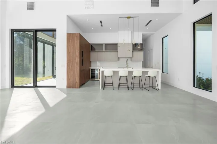 Kitchen featuring modern cabinets, a kitchen breakfast bar, a kitchen island with sink, pendant lighting, and brown cabinetry