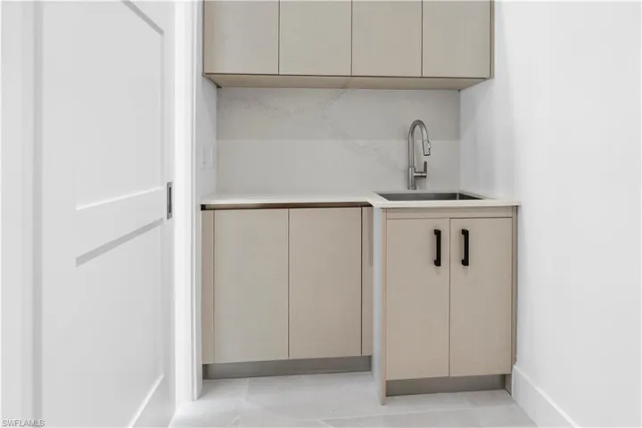 Bar featuring modern cabinets, light stone countertops, and backsplash