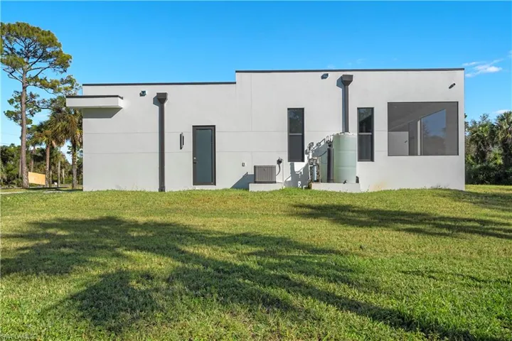 Rear view of house featuring a lawn and stucco siding