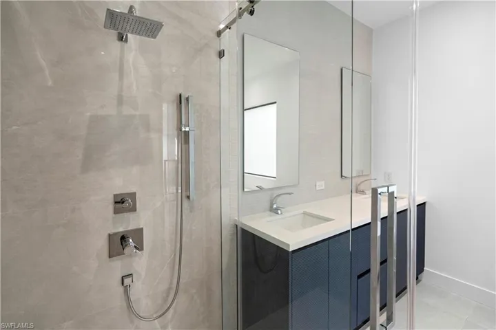 Bathroom featuring double vanity, a shower stall, and light tile patterned floors