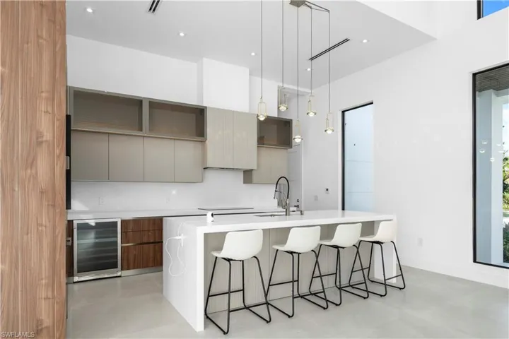 Kitchen featuring modern cabinets, gray cabinets, a kitchen bar, a kitchen island with sink, and recessed lighting