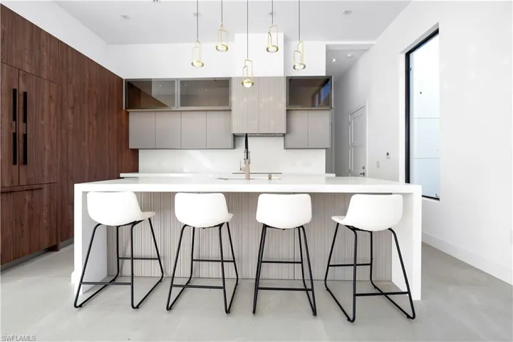 Kitchen with modern cabinets, a breakfast bar, a kitchen island with sink, gray cabinets, and decorative light fixtures