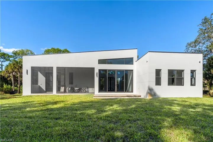 Rear view of property with a yard, stucco siding, and a patio