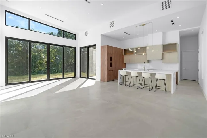 Kitchen with modern cabinets, a breakfast bar, a large island, brown cabinetry, and a high ceiling