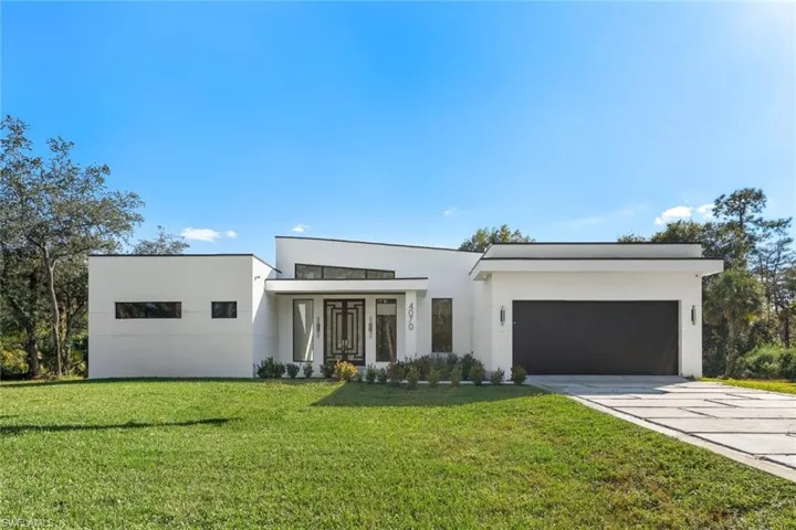 Modern home featuring stucco siding, a front yard, driveway, and a garage