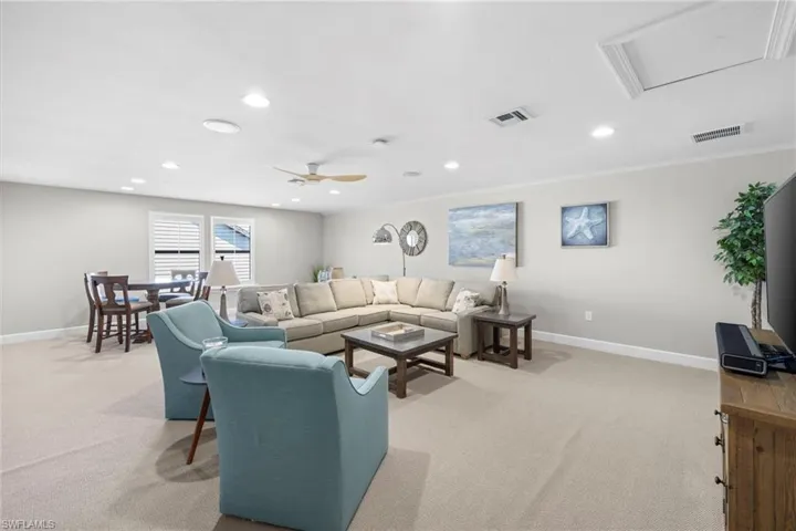 Living area featuring light carpet, recessed lighting, attic access, and a ceiling fan
