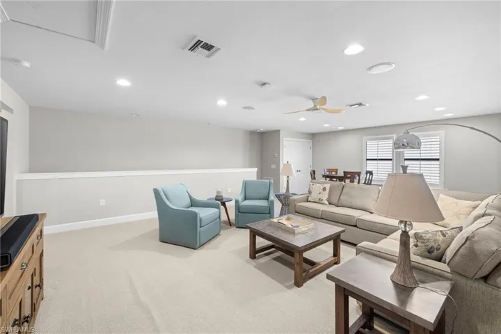 Living area featuring light colored carpet, recessed lighting, and a ceiling fan