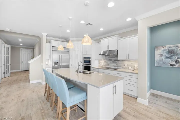 Kitchen featuring ornamental molding, pendant lighting, white cabinetry, a breakfast bar area, and decorative backsplash