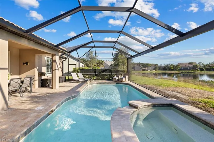 View of pool featuring a patio, a water view, glass enclosure, a sunroom, and a pool with connected hot tub