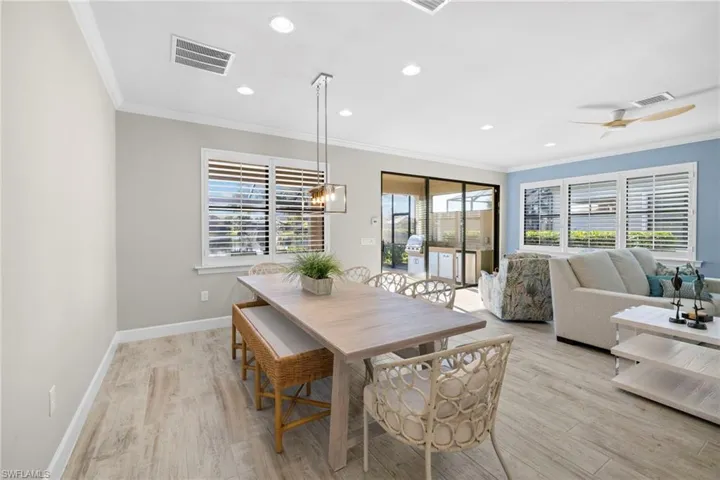 Dining room with crown molding, light wood-type flooring, recessed lighting, a ceiling fan, and a chandelier