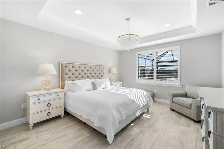 Bedroom featuring a raised ceiling, light wood-style floors, and recessed lighting
