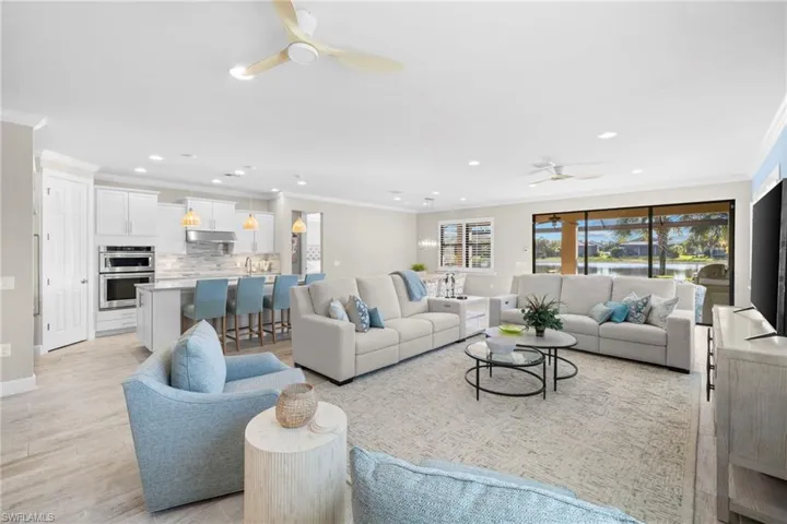 Living room with ornamental molding, a ceiling fan, light wood-style flooring, and recessed lighting