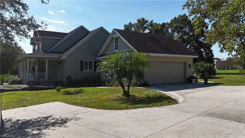 View of front of house with a front lawn, concrete driveway, covered porch, and a garage