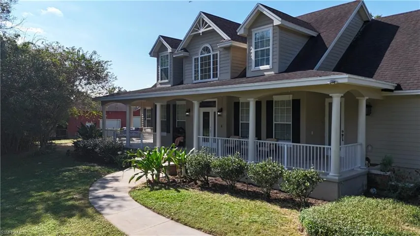 View of front facade with roof with shingles, covered porch, and a front yard