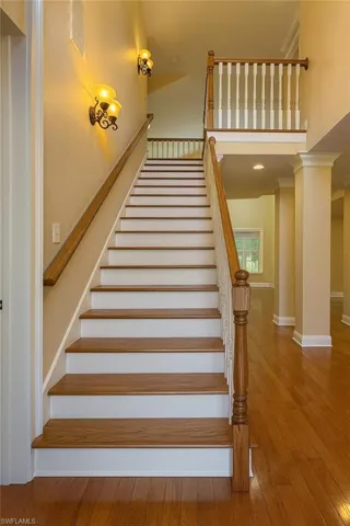 Staircase featuring wood-type flooring, crown molding, and a high ceiling