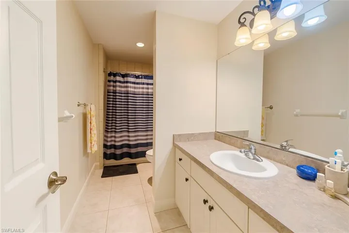 Bathroom with a shower with shower curtain, light tile patterned flooring, vanity, and recessed lighting