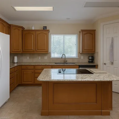 Kitchen featuring light stone countertops, light tile patterned floors, brown cabinets, backsplash, and crown molding