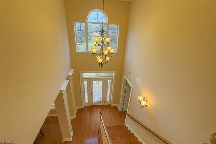 Foyer entrance featuring plenty of natural light, wood finished floors, a high ceiling, a chandelier, and stairway