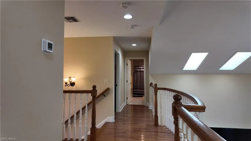 Corridor with dark wood-style floors, recessed lighting, and an upstairs landing