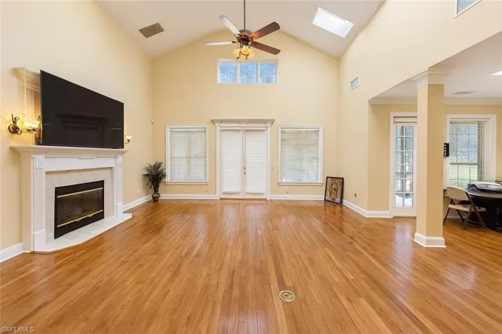 Unfurnished living room with high vaulted ceiling, ceiling fan, light wood-style floors, a high end fireplace, and a skylight
