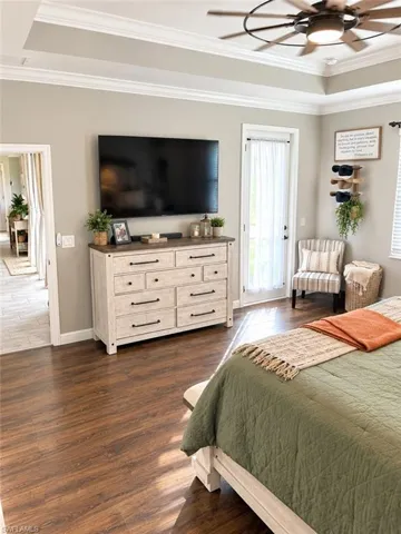 Tray ceiling with crown molding, wood-finish flooring, ceiling fan, and recessed lighting