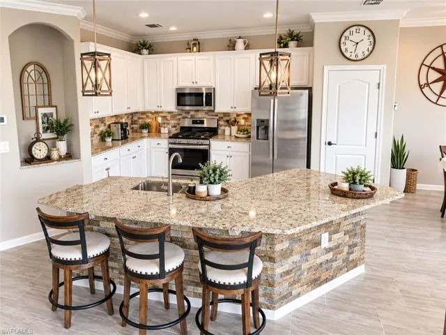 Kitchen featuring white cabinetry, stainless steel appliances, a stone backsplash, and granite countertops