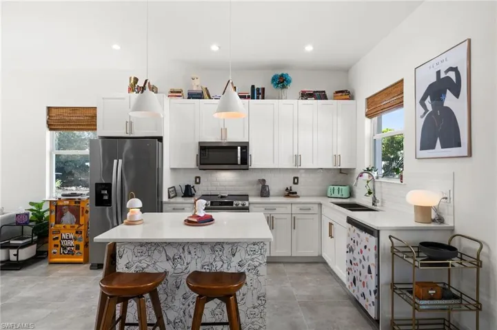 Kitchen with pendant lighting, sink, white cabinetry, and stainless steel appliances