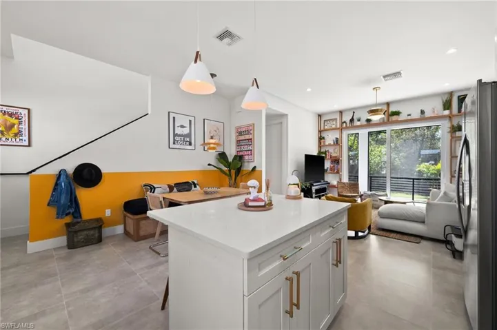Kitchen featuring white cabinets, decorative light fixtures, a breakfast bar, and stainless steel refrigerator