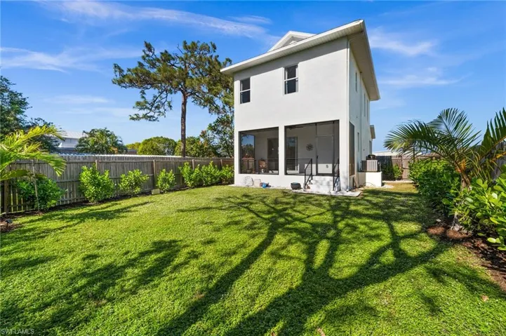 Rear view of property featuring a sunroom, a yard, and central AC