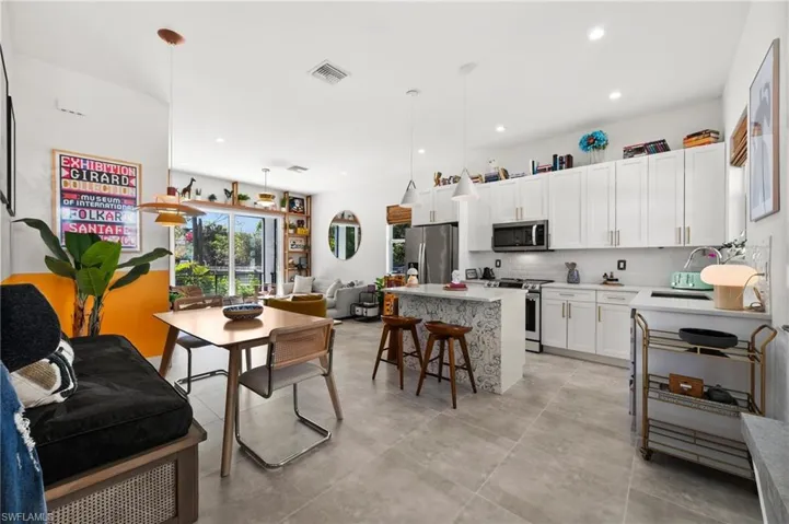 Kitchen featuring white cabinetry, hanging light fixtures, stainless steel appliances, a breakfast bar, and a kitchen island