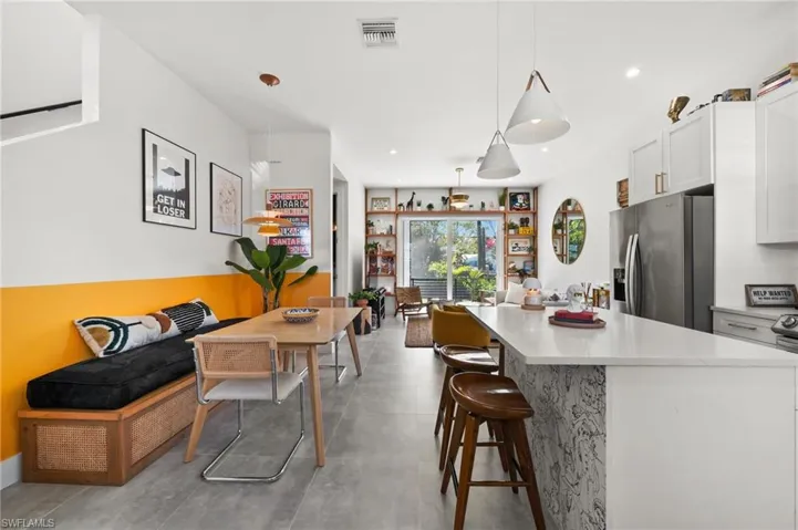 Kitchen featuring pendant lighting, a breakfast bar, stainless steel fridge, and white cabinetry