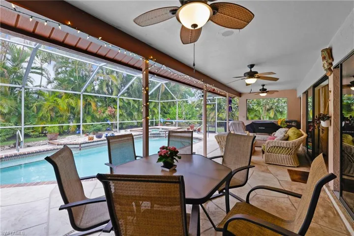 View of patio featuring a lanai, ceiling fan, and a pool with hot tub