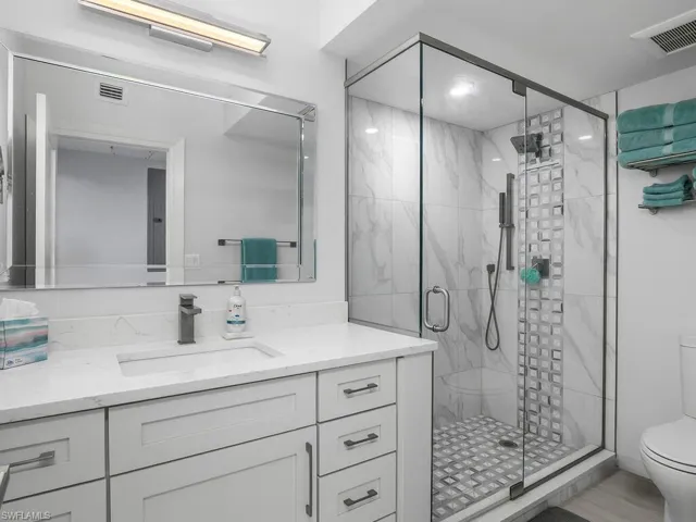 Bathroom featuring vanity and a marble finish shower