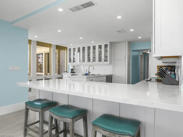 Kitchen with a breakfast bar area, light stone countertops, a peninsula, and recessed lighting