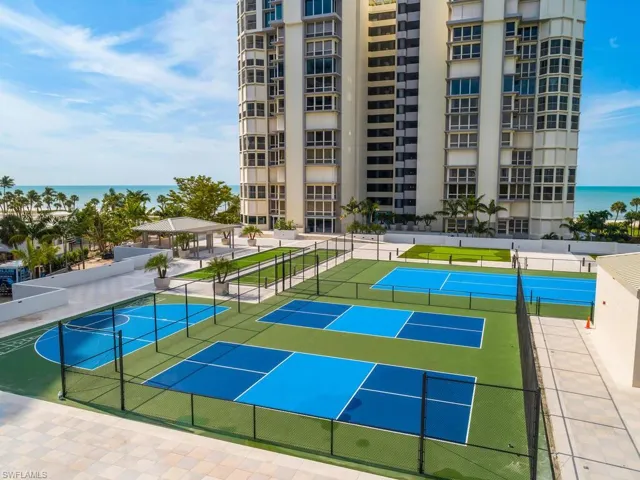 View of tennis court featuring a patio and a water view