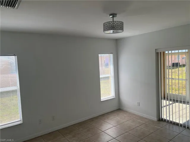 Unfurnished room with visible vents, tile patterned flooring, and a healthy amount of sunlight
